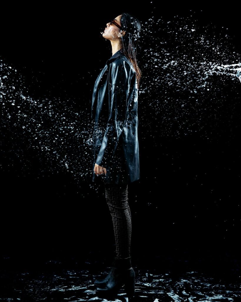 Striking studio fashion shot featuring water splash effect on leather jacket model.