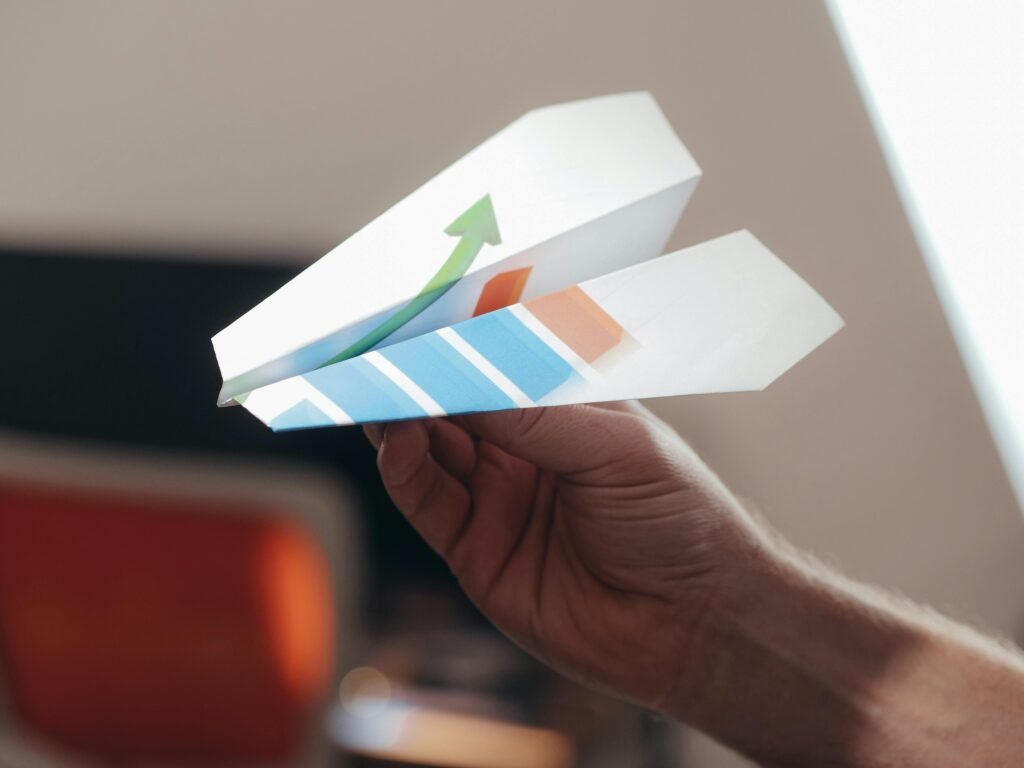 A close-up view of a hand holding a paper airplane with colorful graphics.