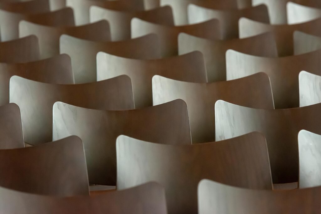 Symmetrical rows of wooden chairs creating a rhythmic and abstract pattern indoors.