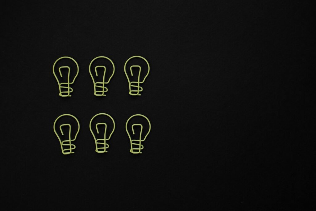 Set of light bulb shaped paper clips on black background with copy space.