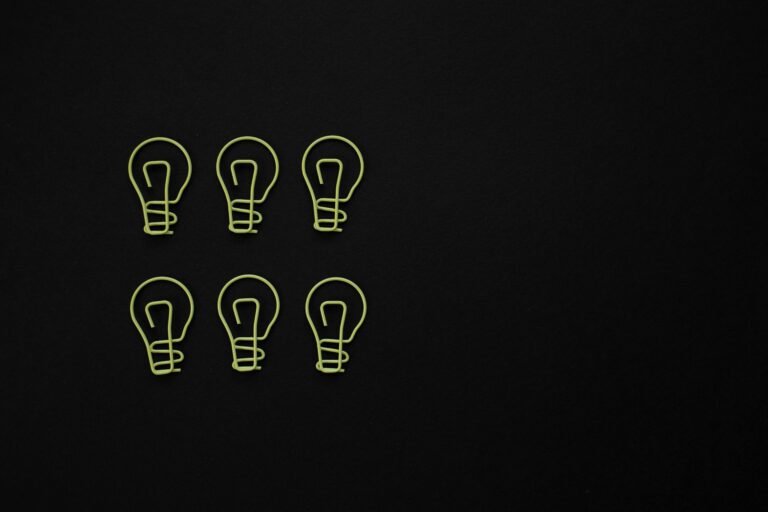 Set of light bulb shaped paper clips on black background with copy space.