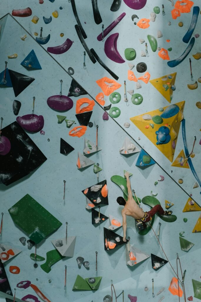 Man climbing on colorful indoor rock wall, showcasing strength.