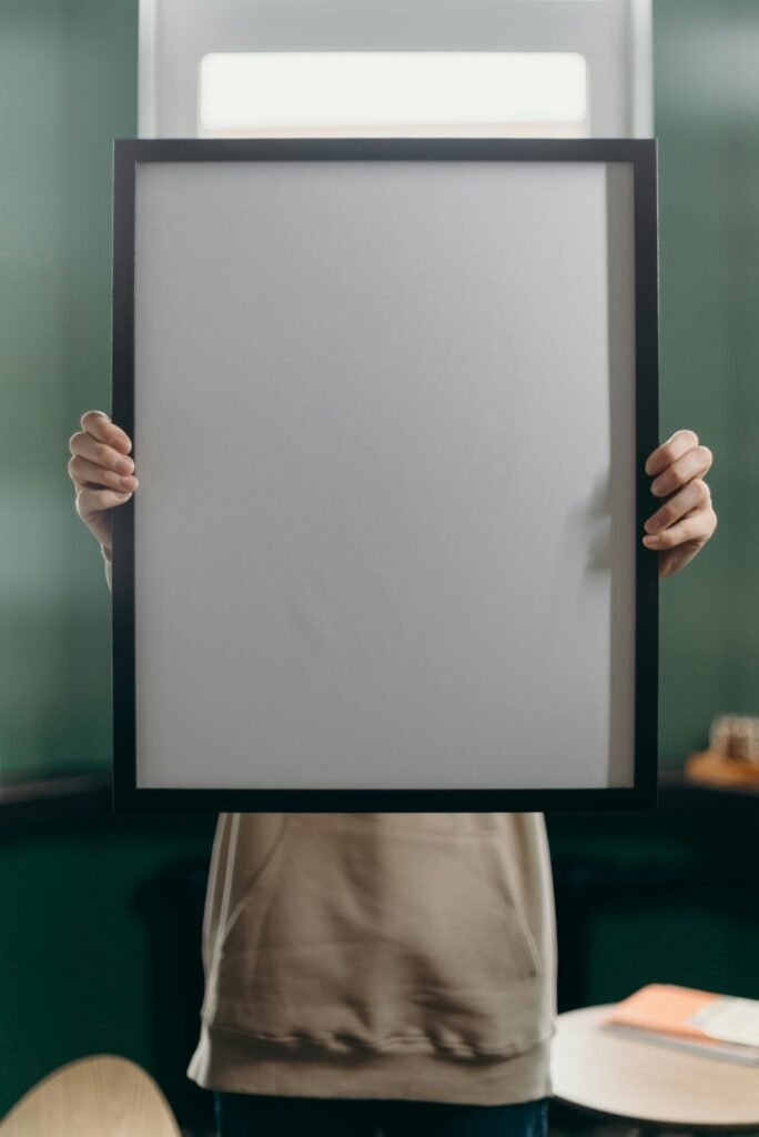 An anonymous individual holding a blank black frame, perfect for art or photo mockups.
