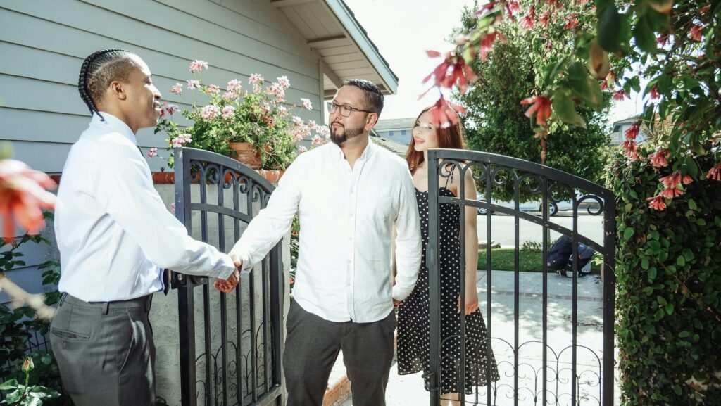 A real estate agent meets a couple at their new home, symbolizing a successful property transaction.